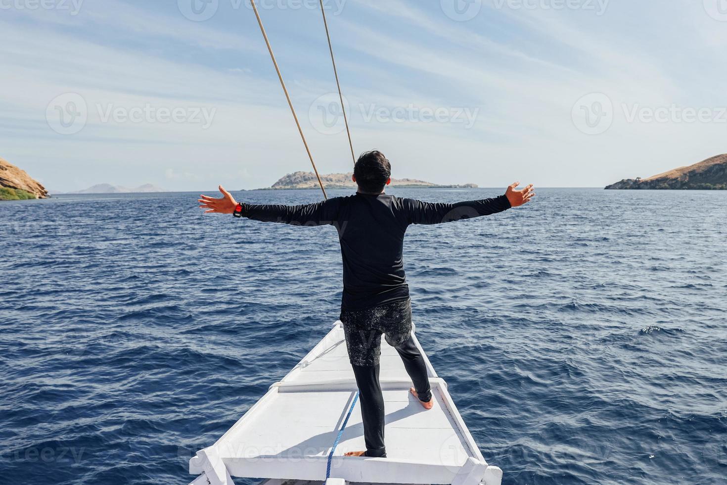 un hombre con traje de neopreno parado en el bote y disfrutando de las vacaciones de verano foto