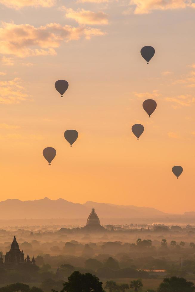 grupo de globos aerostáticos que vuelan sobre la antigua pagoda en la llanura de bagan al amanecer. bagan ahora es el sitio del patrimonio mundial de la unesco y el primer reino de myanmar. foto