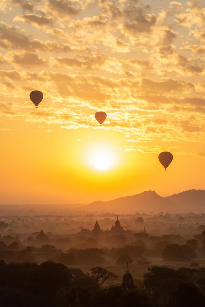 grupo de globos aerostáticos que vuelan sobre la antigua pagoda en la llanura de bagan al amanecer. bagan ahora es el sitio del patrimonio mundial de la unesco y el primer reino de myanmar. foto