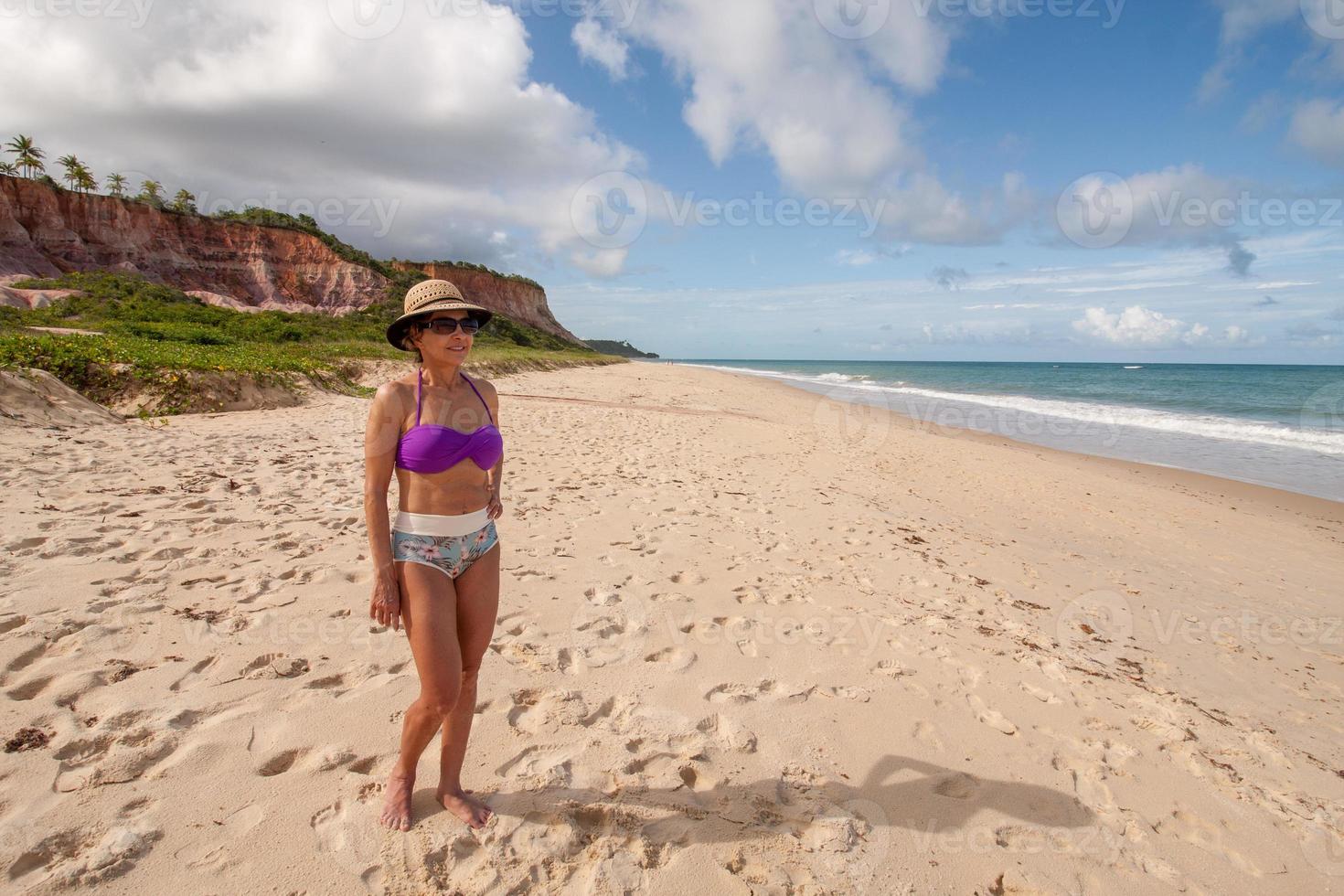 Lady standing at the beach known as Taipe with the colorful cliffs in the background near Arraial d Ajuda, Biaha, Brazil photo
