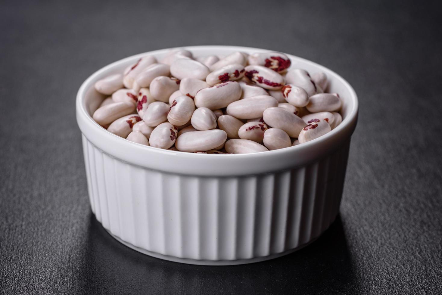 White dry raw beans on a dark concrete background photo