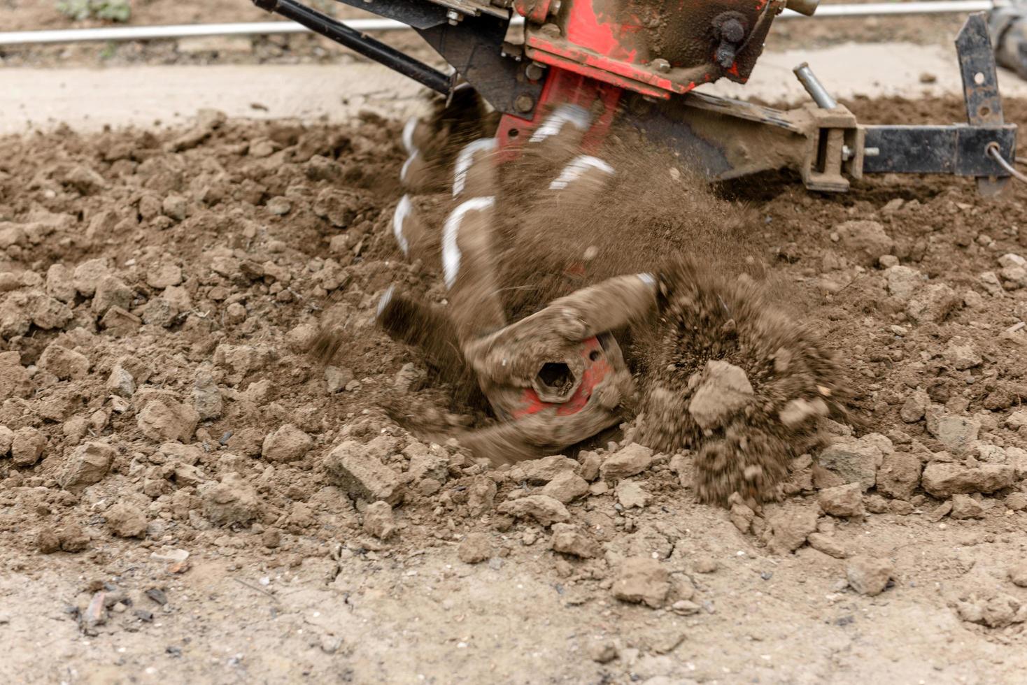 Small farm tractor plows the ground, the work of a walk-behind tractor photo