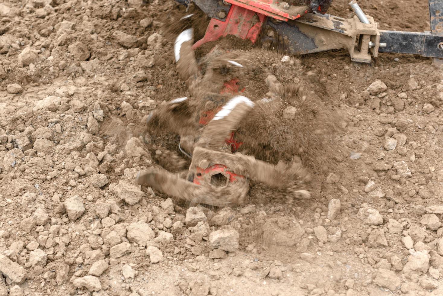 Small farm tractor plows the ground, the work of a walk-behind tractor photo