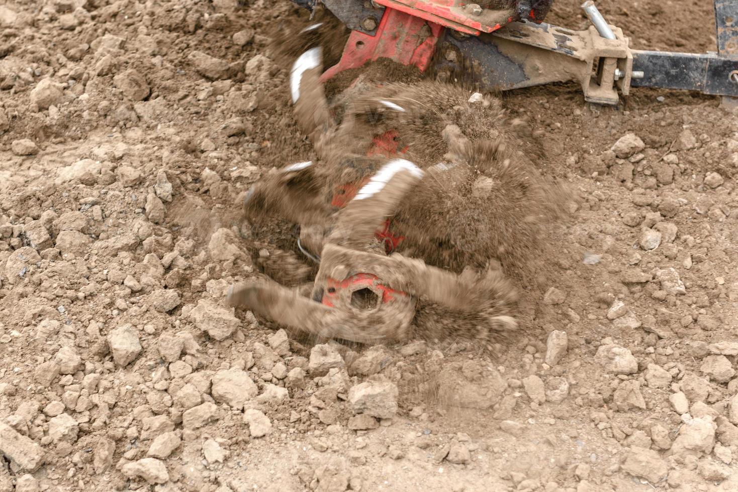 Small farm tractor plows the ground, the work of a walk-behind tractor photo