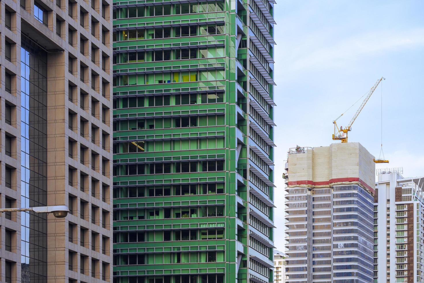 Focus on foreground at row of high residential buildings with blue sky in perspective side view that one building is under construction photo