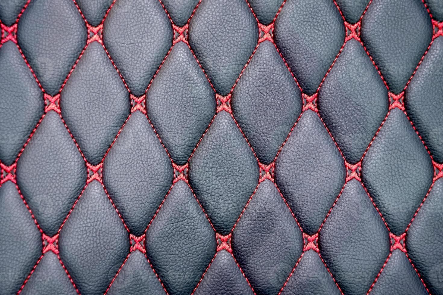 Close up red thread lines in rhombus pattern on surface of black genuine leather car seat background photo