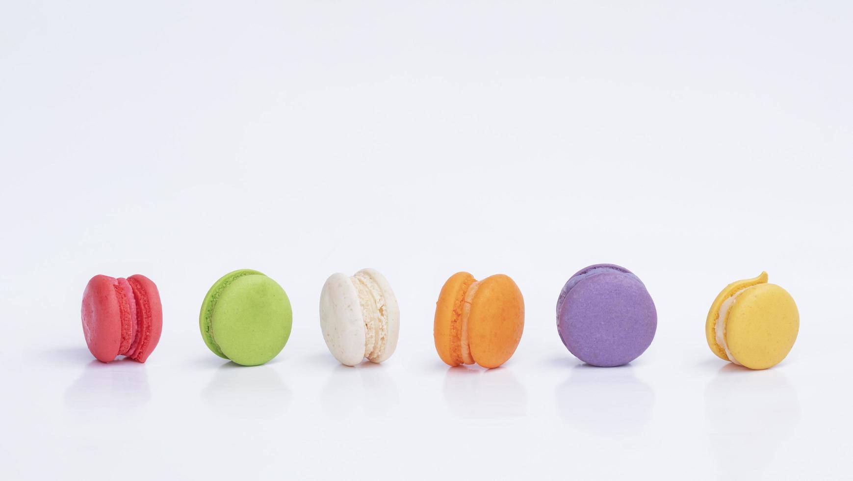 Row of mini colorful macarons on white background photo