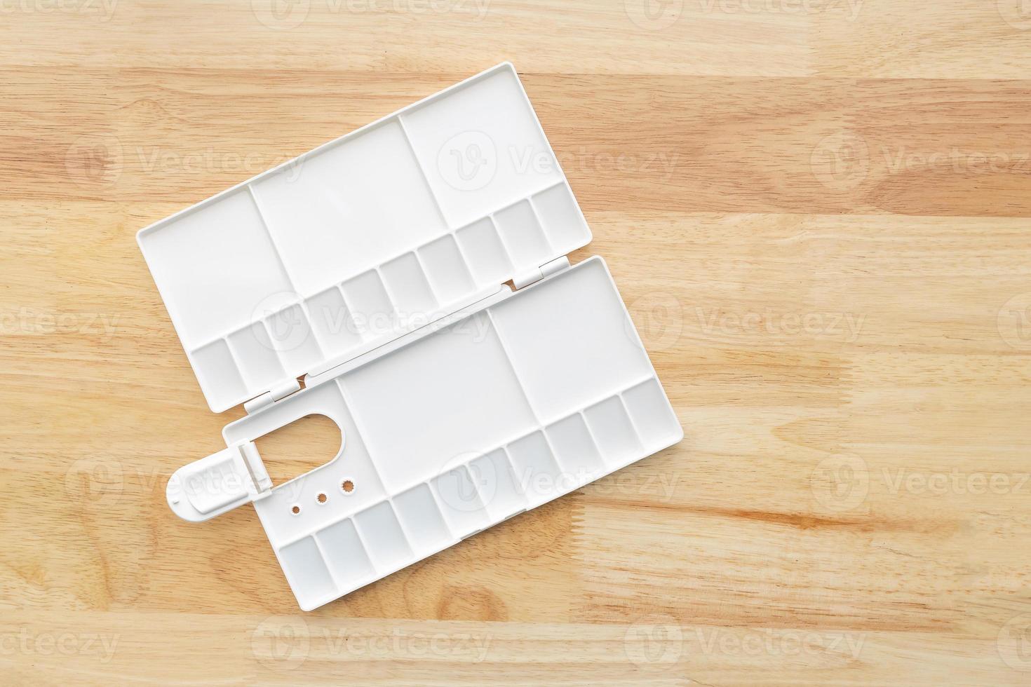 White watercolor palette. Empty watercolor tray isolated on wood background. photo