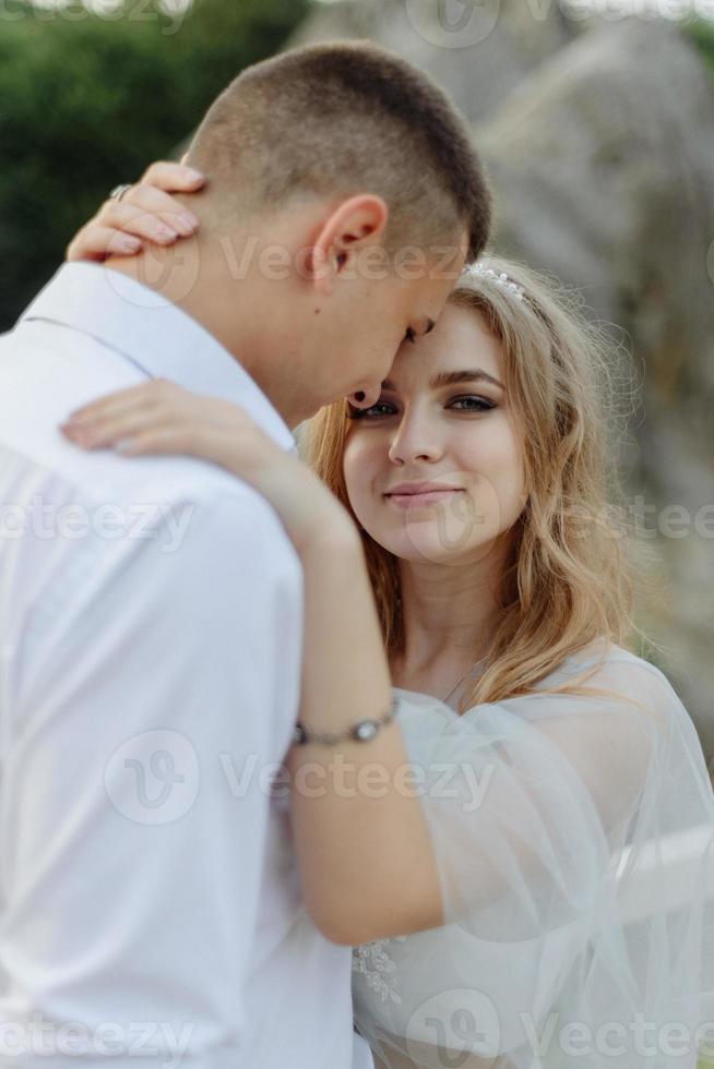 sesión de fotos de una pareja enamorada en las montañas. la niña está vestida como una novia con un vestido de novia.