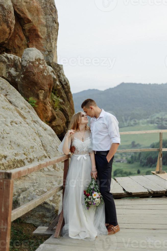 sesión de fotos de una pareja enamorada en las montañas. la niña está vestida como una novia con un vestido de novia.
