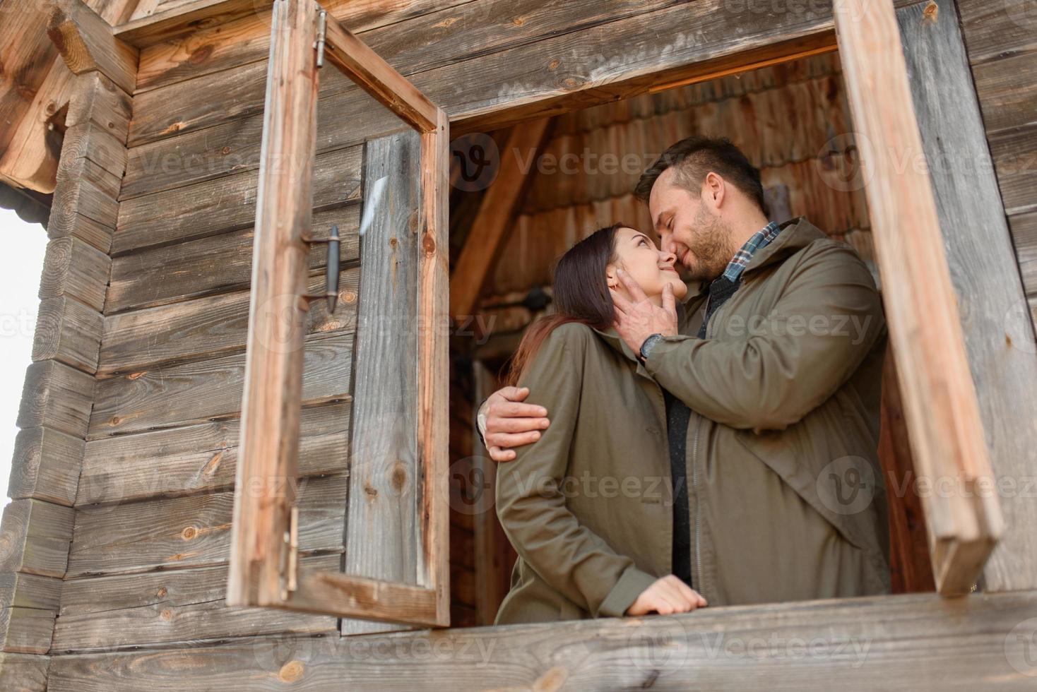 couple in love looks out of the window, wooden house. The concept of buying new housing for young families. photo