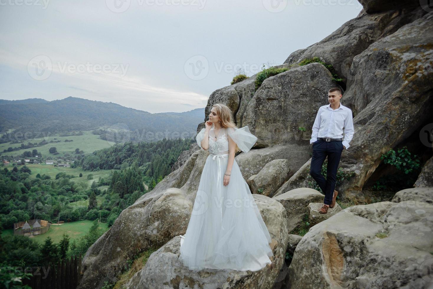 sesión de fotos de una pareja enamorada en las montañas. la niña está vestida como una novia con un vestido de novia.