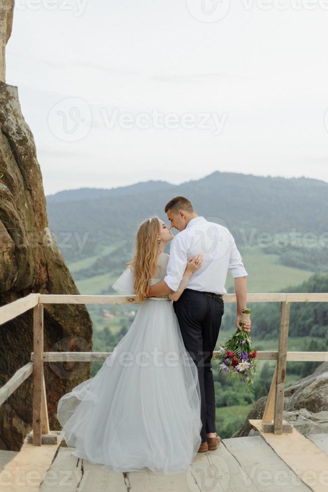 sesión de fotos de una pareja enamorada en las montañas. la niña está vestida como una novia con un vestido de novia.