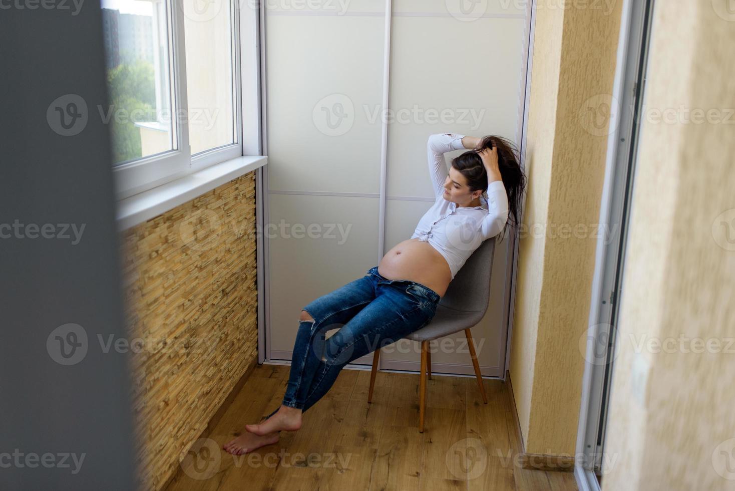 A man and a pregnant woman are sitting hugging on the couch. photo