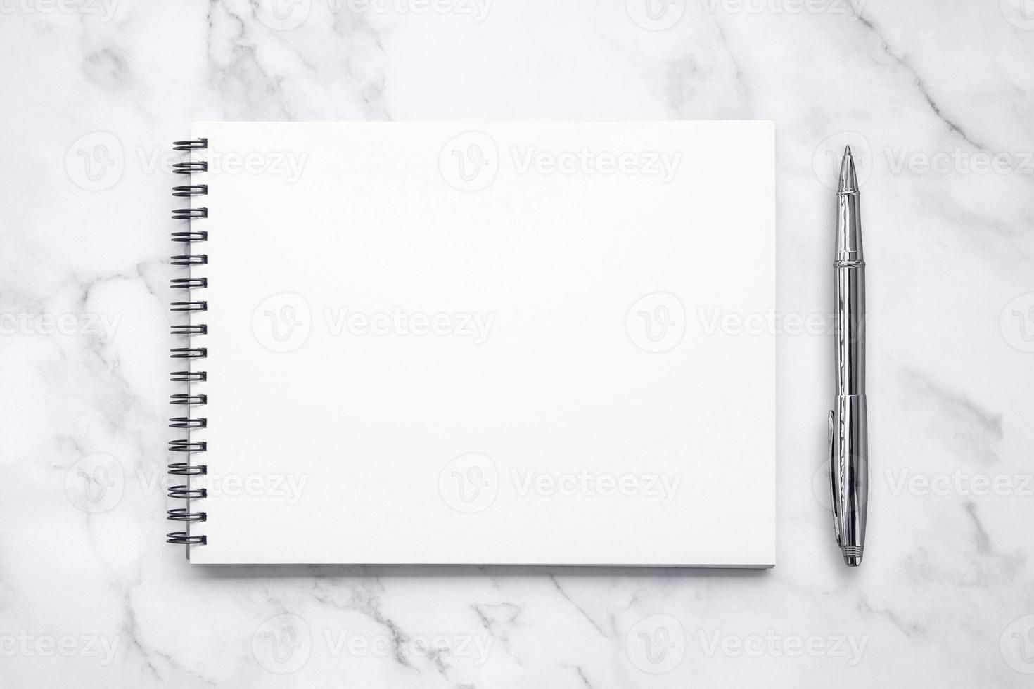 Notepad amd a pen on white marble table background. photo