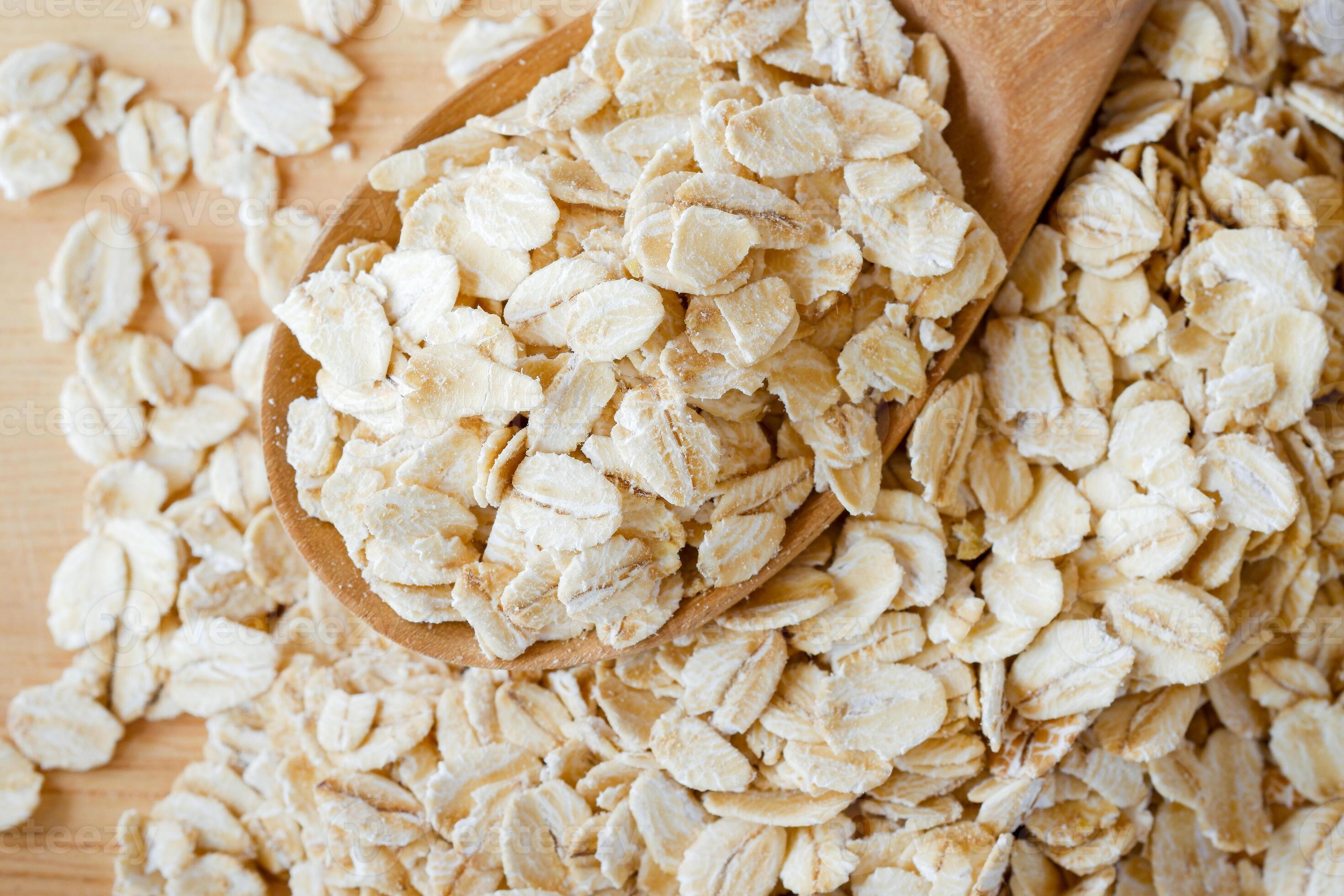 Close-up rolled oats in a wooden spoon on a oats pile. Healthy food ...