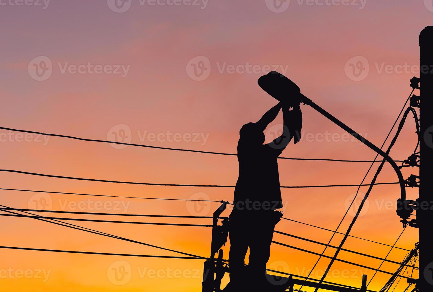 Silhouette of Electrician checking lighting to the LED street lamp post, Technician with clipping path and maintenance service concepts photo