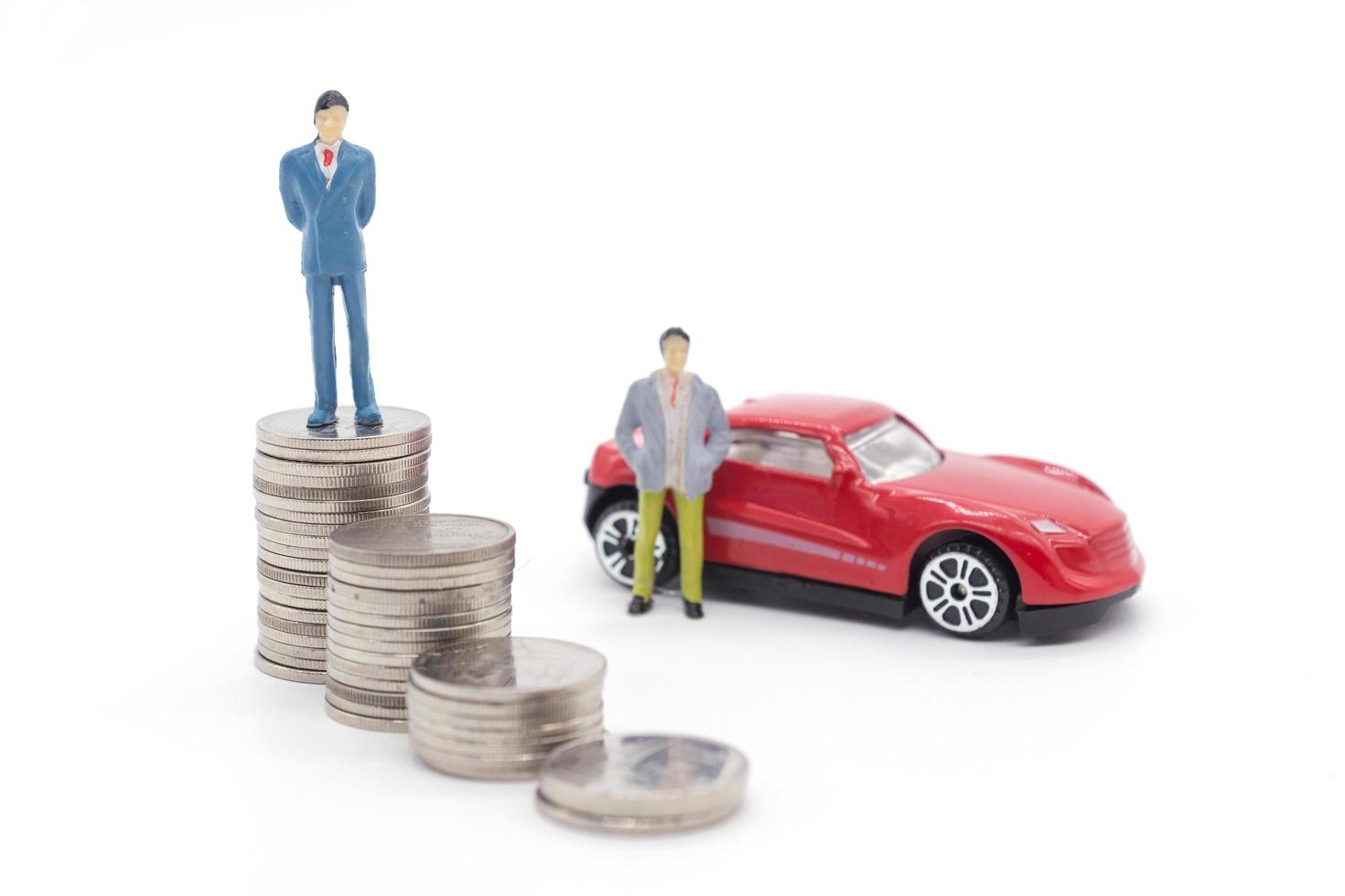 Miniature businessman standing on coins and the car behind. saving and loan concept. photo