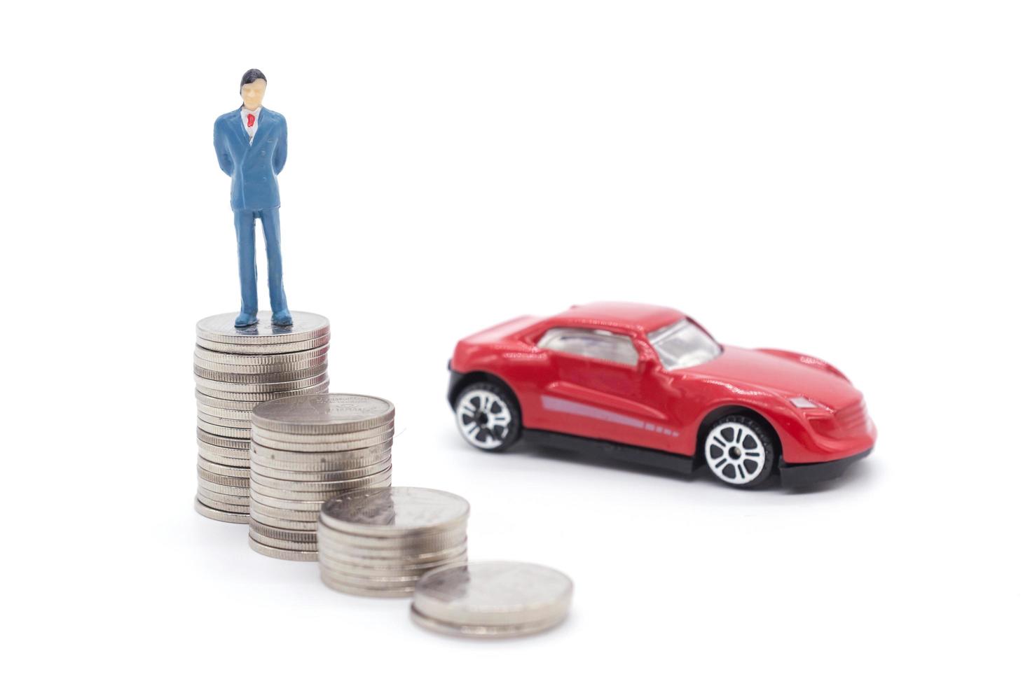 Miniature businessman standing on coins and the car behind. saving and loan concept. photo