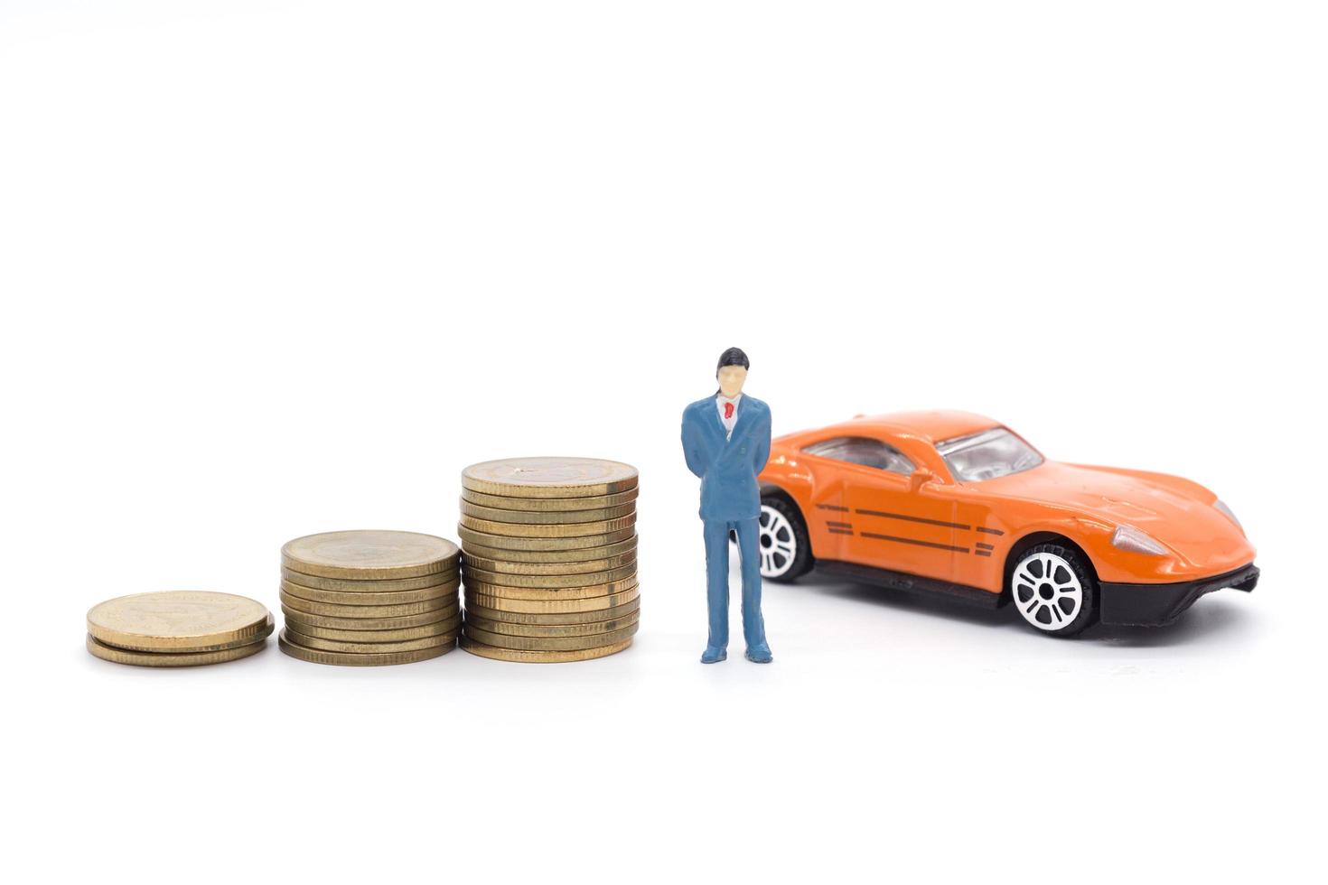 Miniature businessman standing on coins and the car behind. saving and loan concept. photo