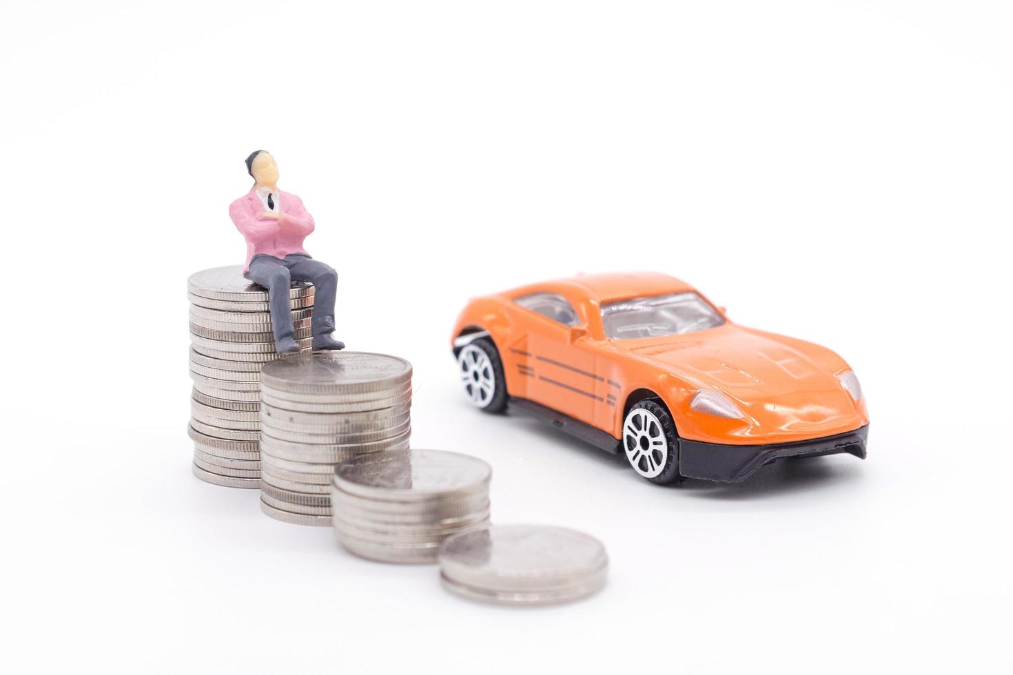 Miniature businessman standing on coins and the car behind. saving and loan concept. photo