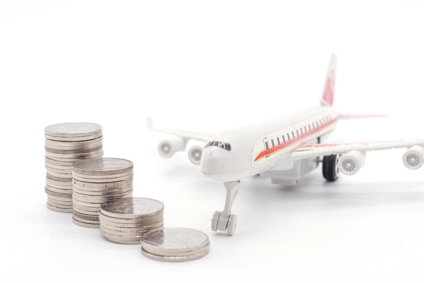 Airplane and stack coins on white background photo