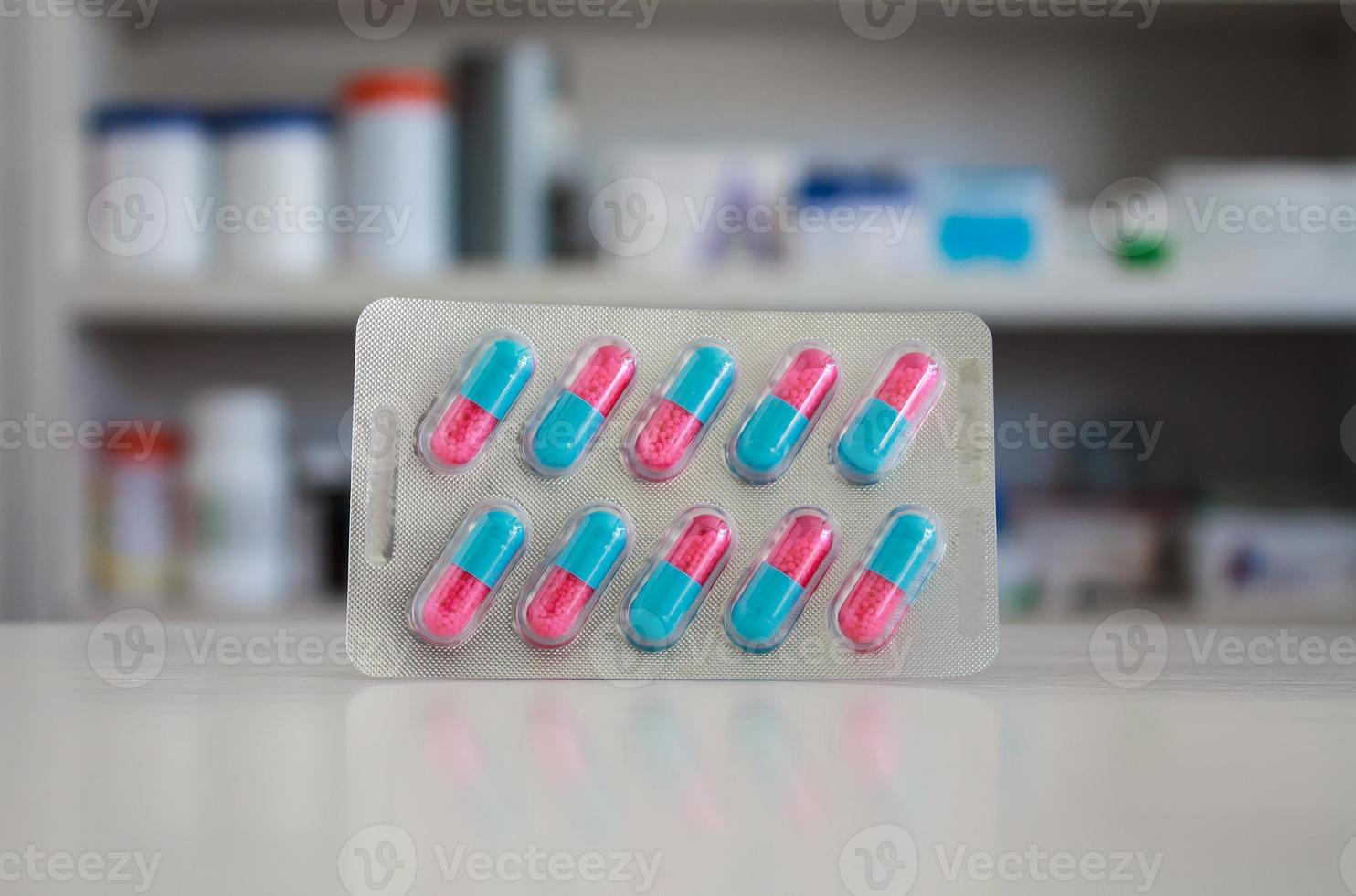 Píldoras de cápsulas de colores con estantes borrosos de drogas en el fondo de la farmacia foto