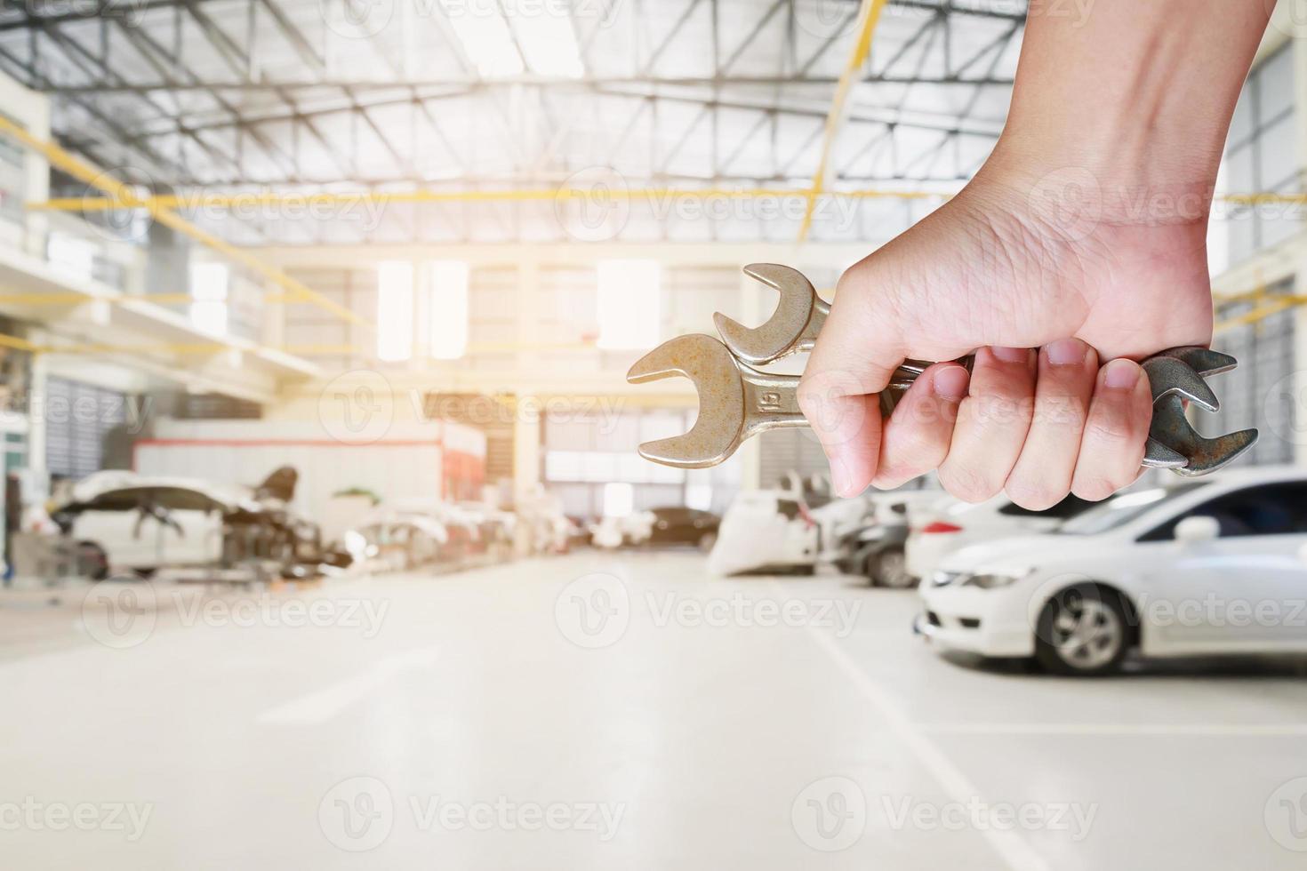 mechanic holding wrench over car repair service centre photo