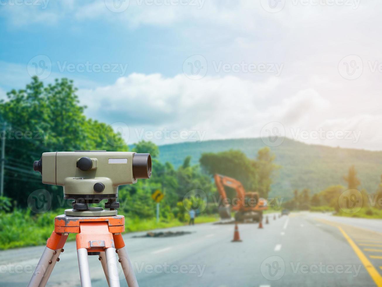 Tacómetro o teodolito del equipo topógrafo con fondo de obra de construcción de carreteras foto