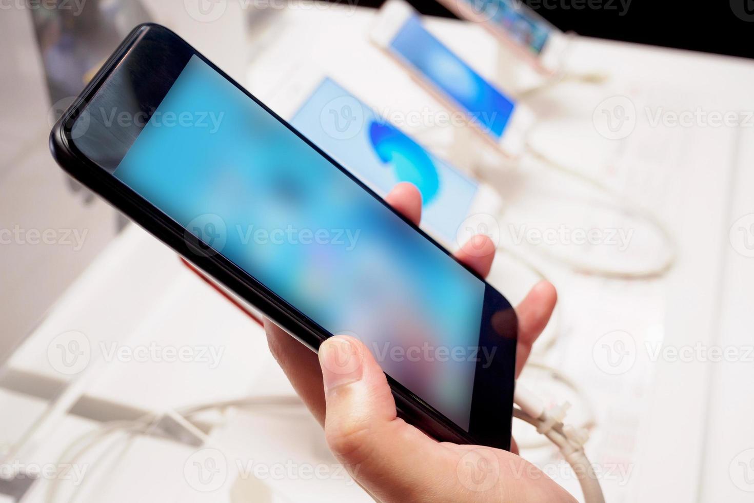 mujer eligiendo un nuevo teléfono inteligente móvil en la tienda foto