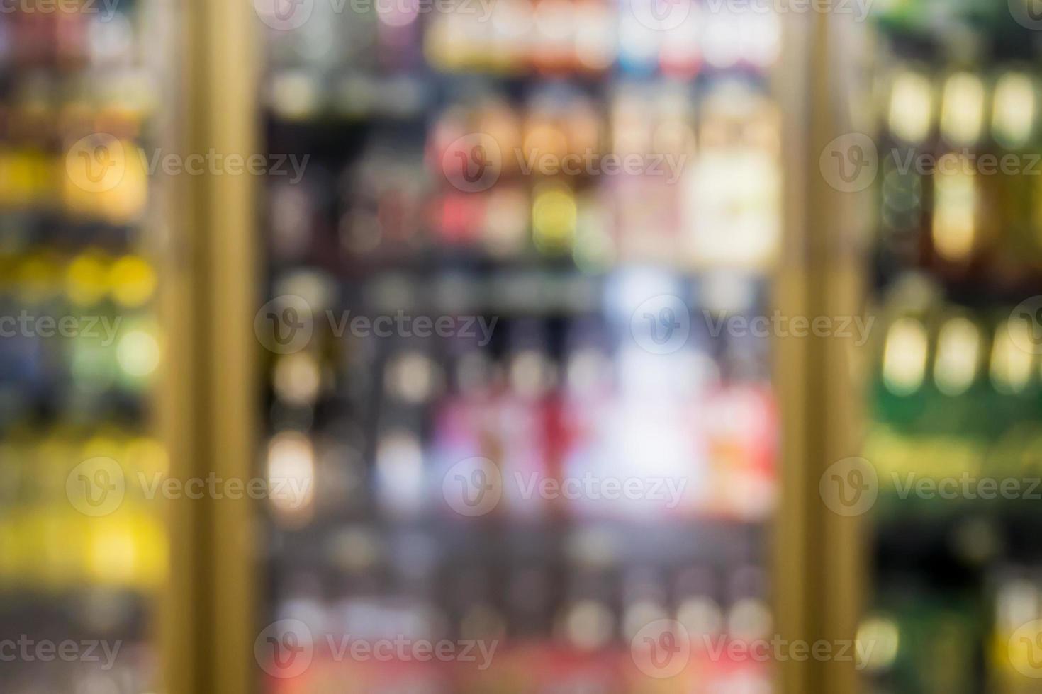 desenfoque de botellas de bebida en los estantes del congelador en el supermercado foto