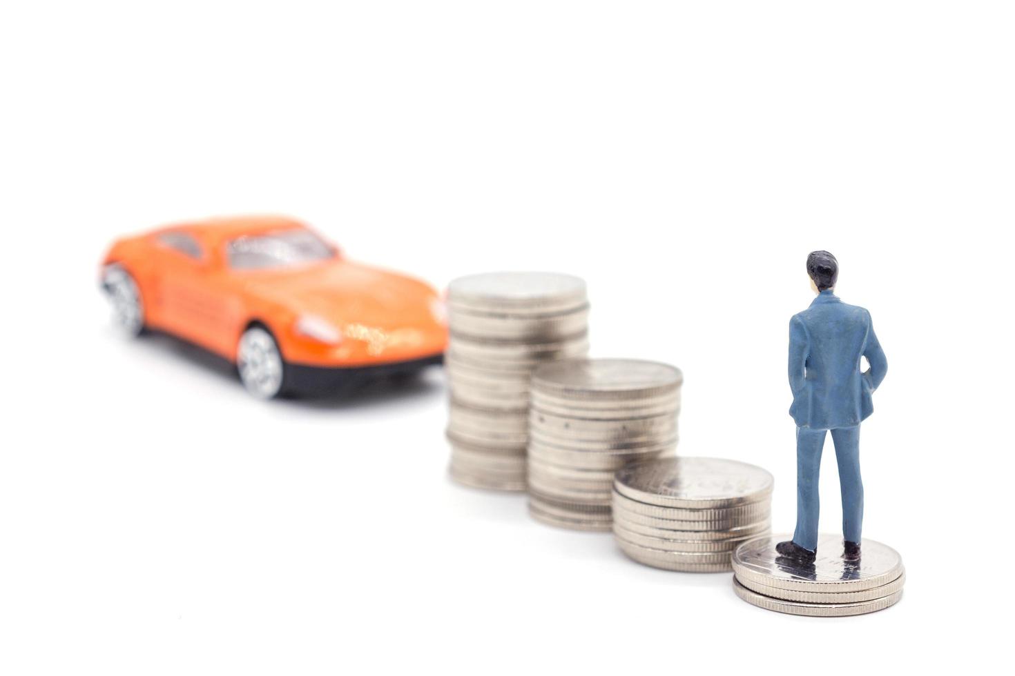 Miniature businessman standing on coins and the car behind. saving and loan concept. photo