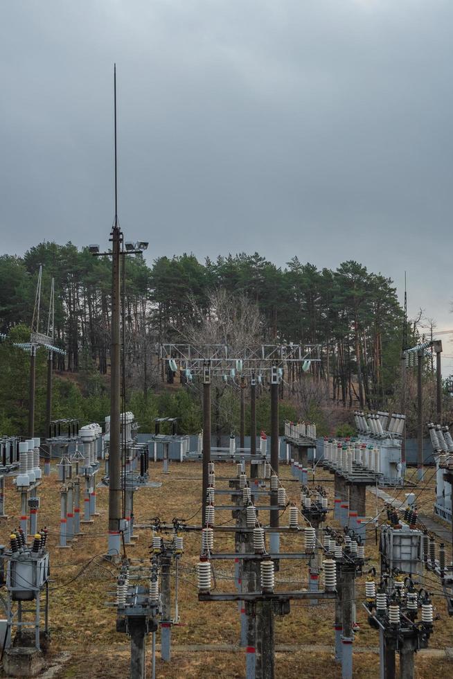 Small high-voltage electrical substation in a coniferous forest in cloudy weather. photo