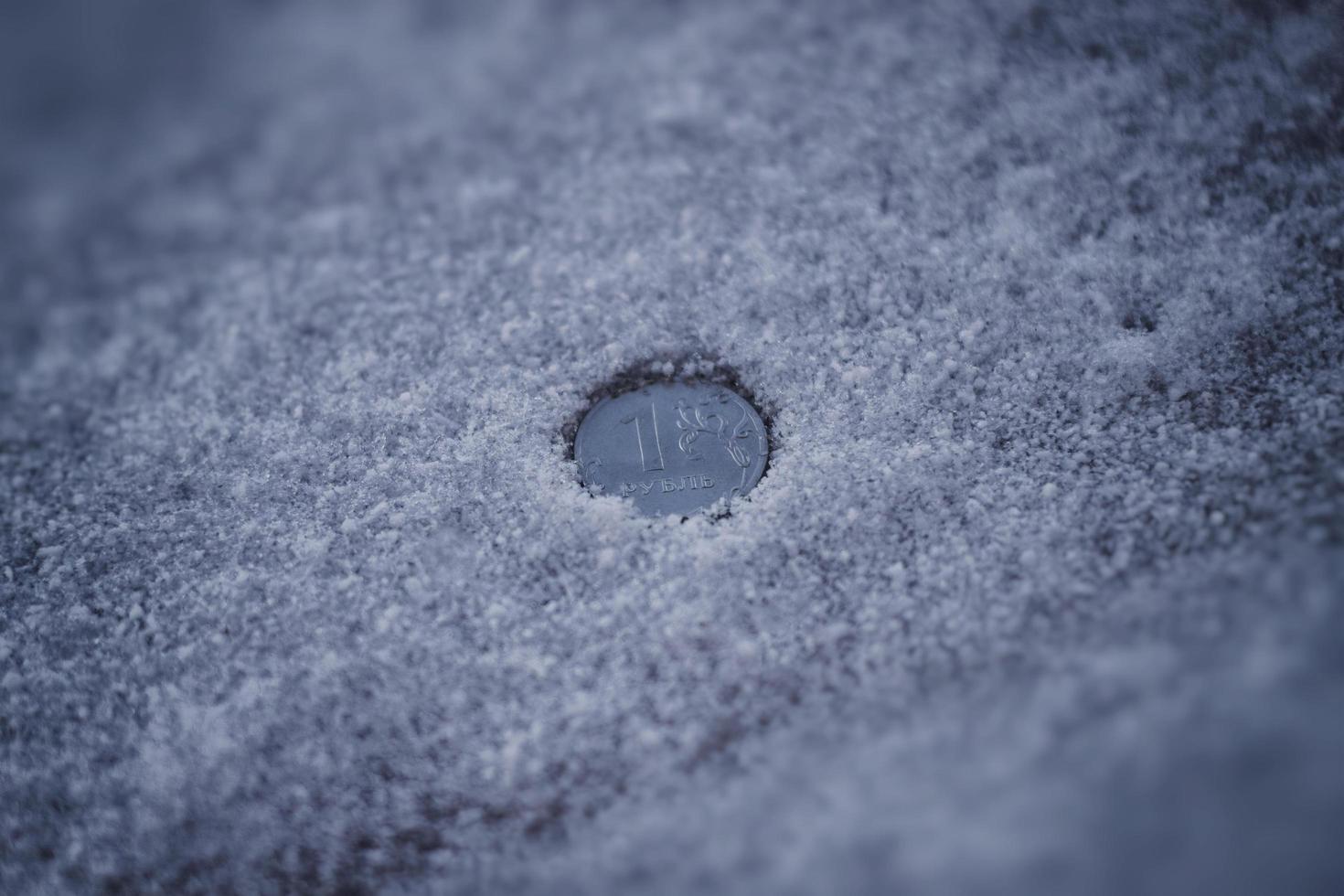 moneda de rublo entre nieve sucia y cenizas. foto