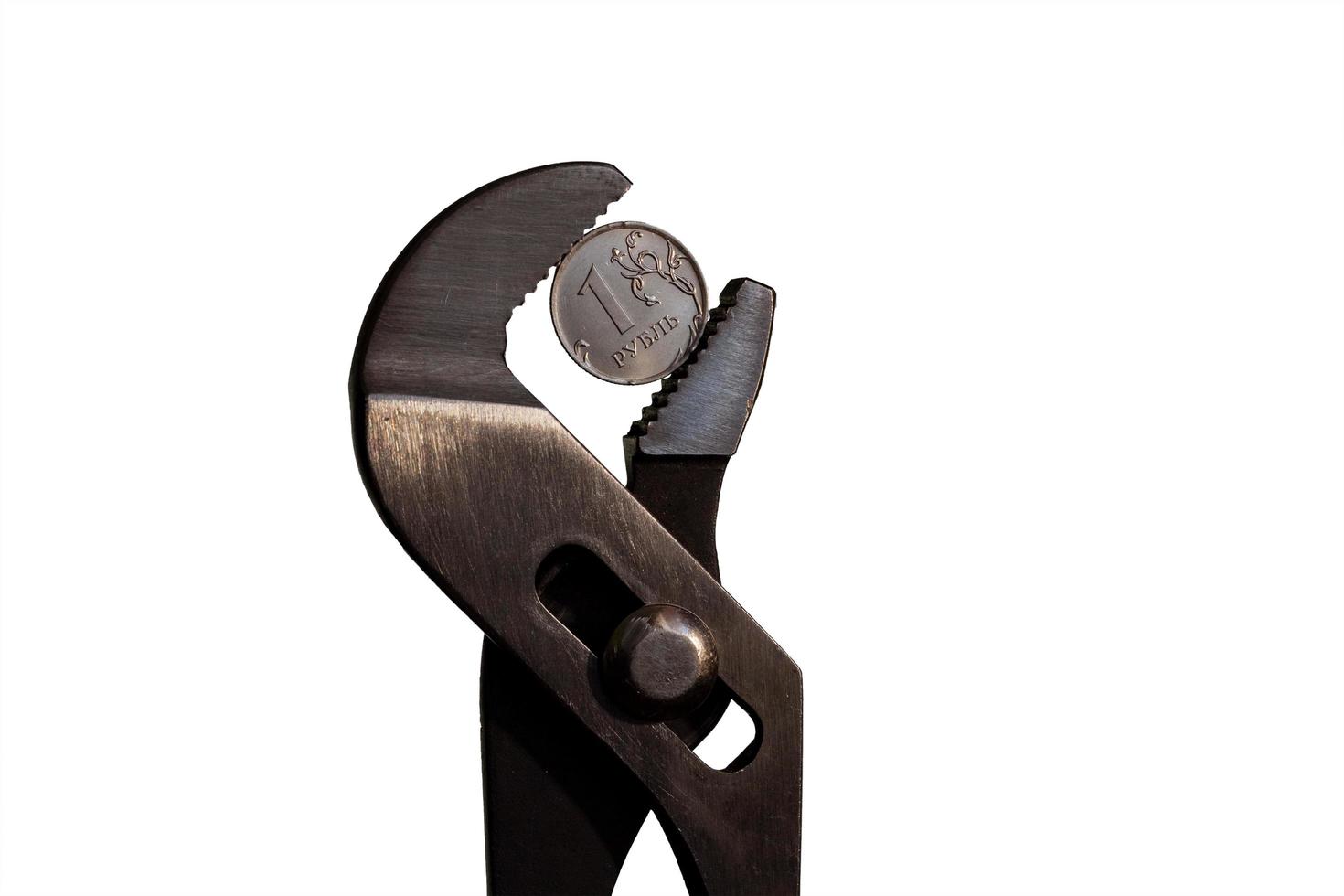 Coin one ruble is clamped in a wrench against the white background. The idea of the collapse of the ruble and economy sanctions against Russia. photo
