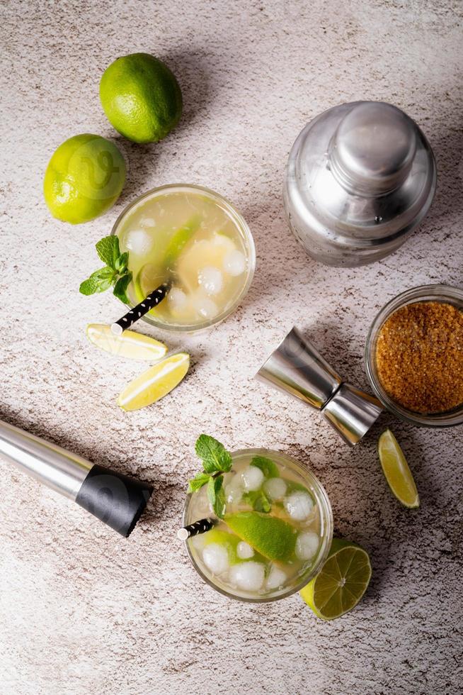 Cóctel de caipirinha de verano fresco sobre fondo de hormigón con ingredientes, vista superior foto