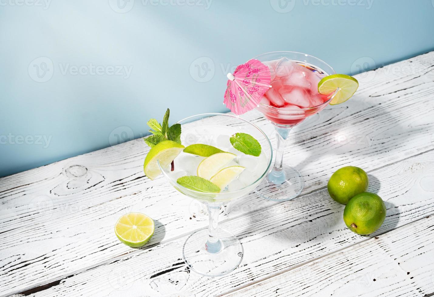 Fresh summer cocktails with strawberry, lime and ice cubes on blue background with copy space photo
