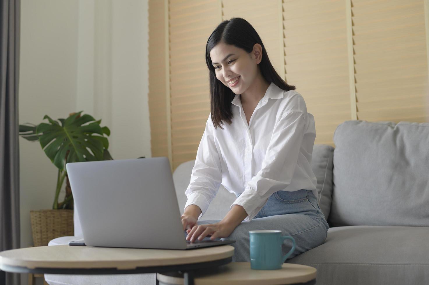 joven hermosa mujer está trabajando con su computadora en casa. foto