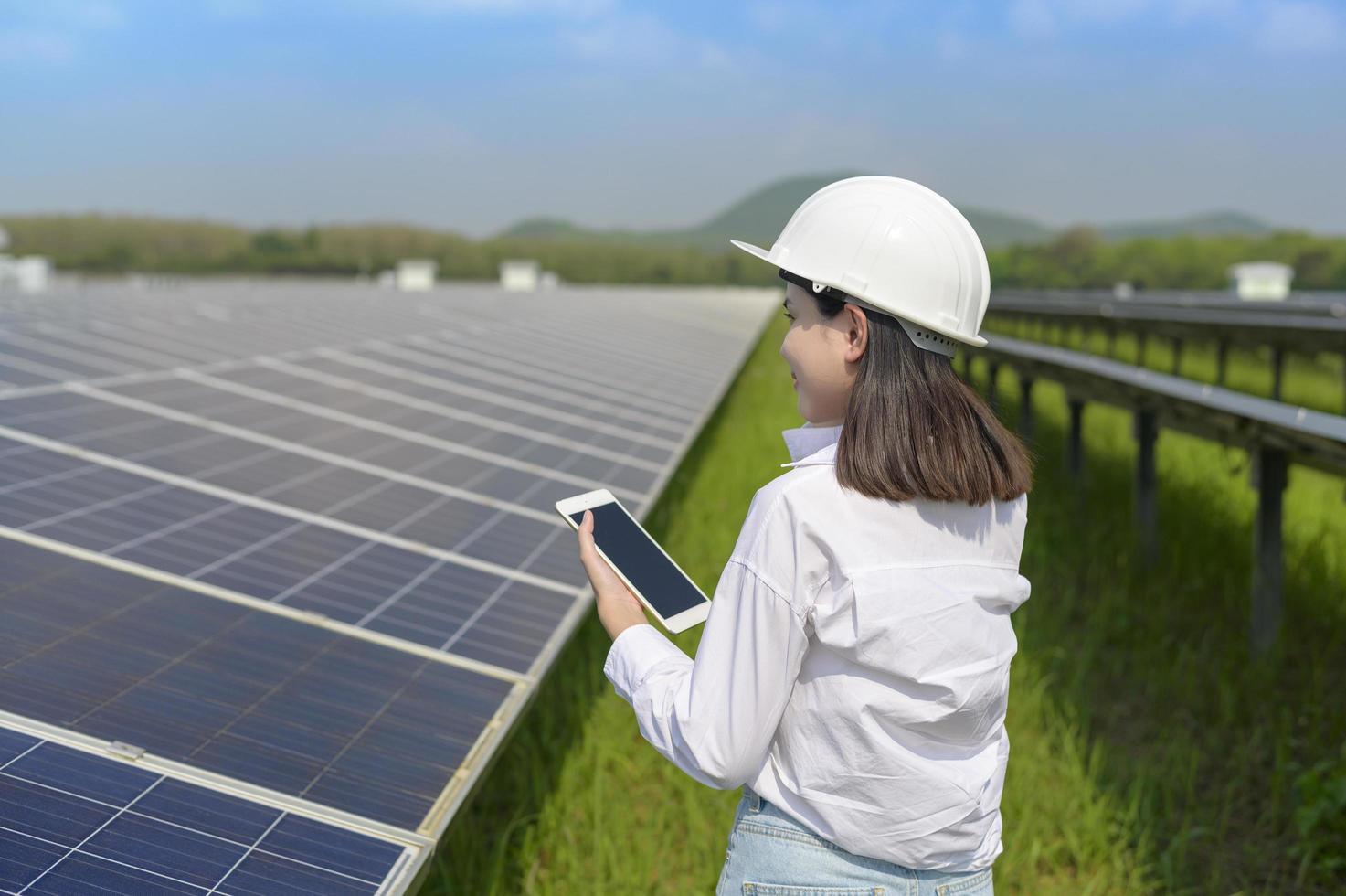 Female engineer wearing helmet in Photovoltaic Cell Farm or Solar Panels Field, eco friendly and clean energy. photo