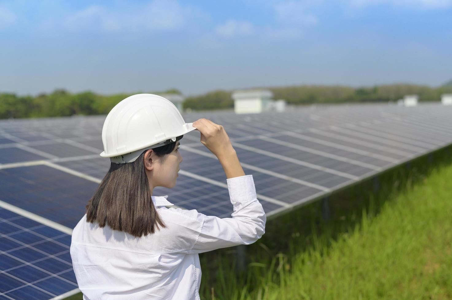 Female engineer wearing helmet in Photovoltaic Cell Farm or Solar Panels Field, eco friendly and clean energy. photo