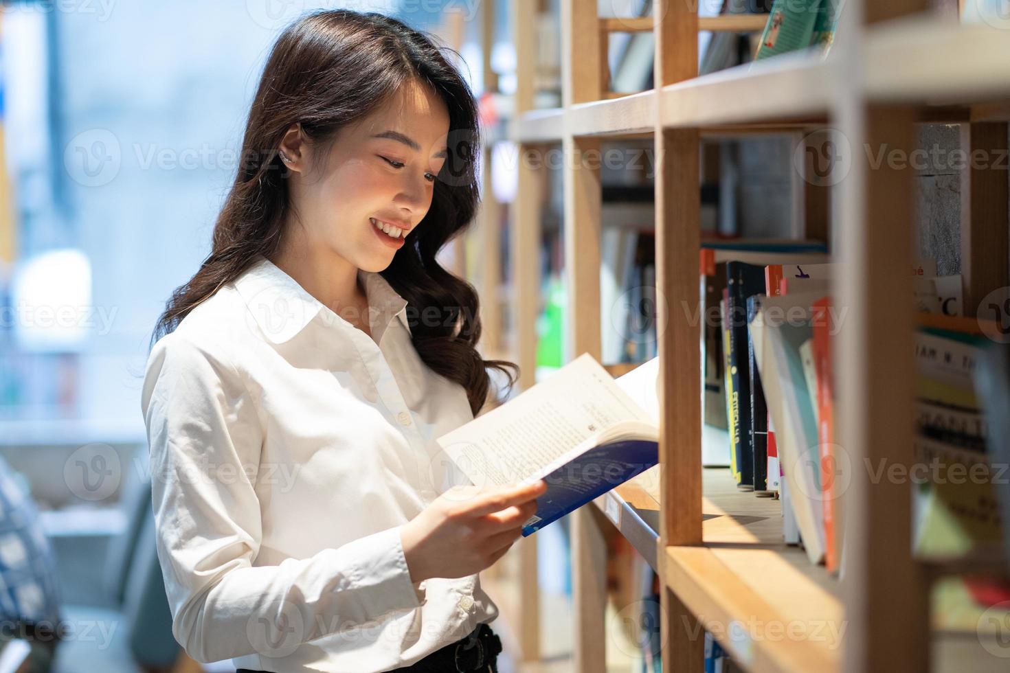 imagen de una mujer de negocios asiática leyendo un libro en la biblioteca foto