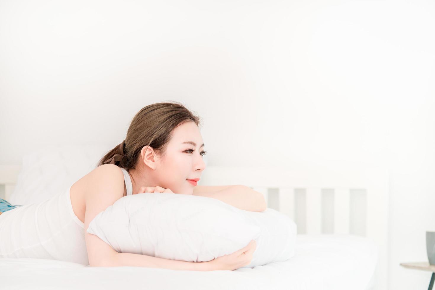hermosa joven asiática con el pelo largo durmiendo en una cama blanca foto