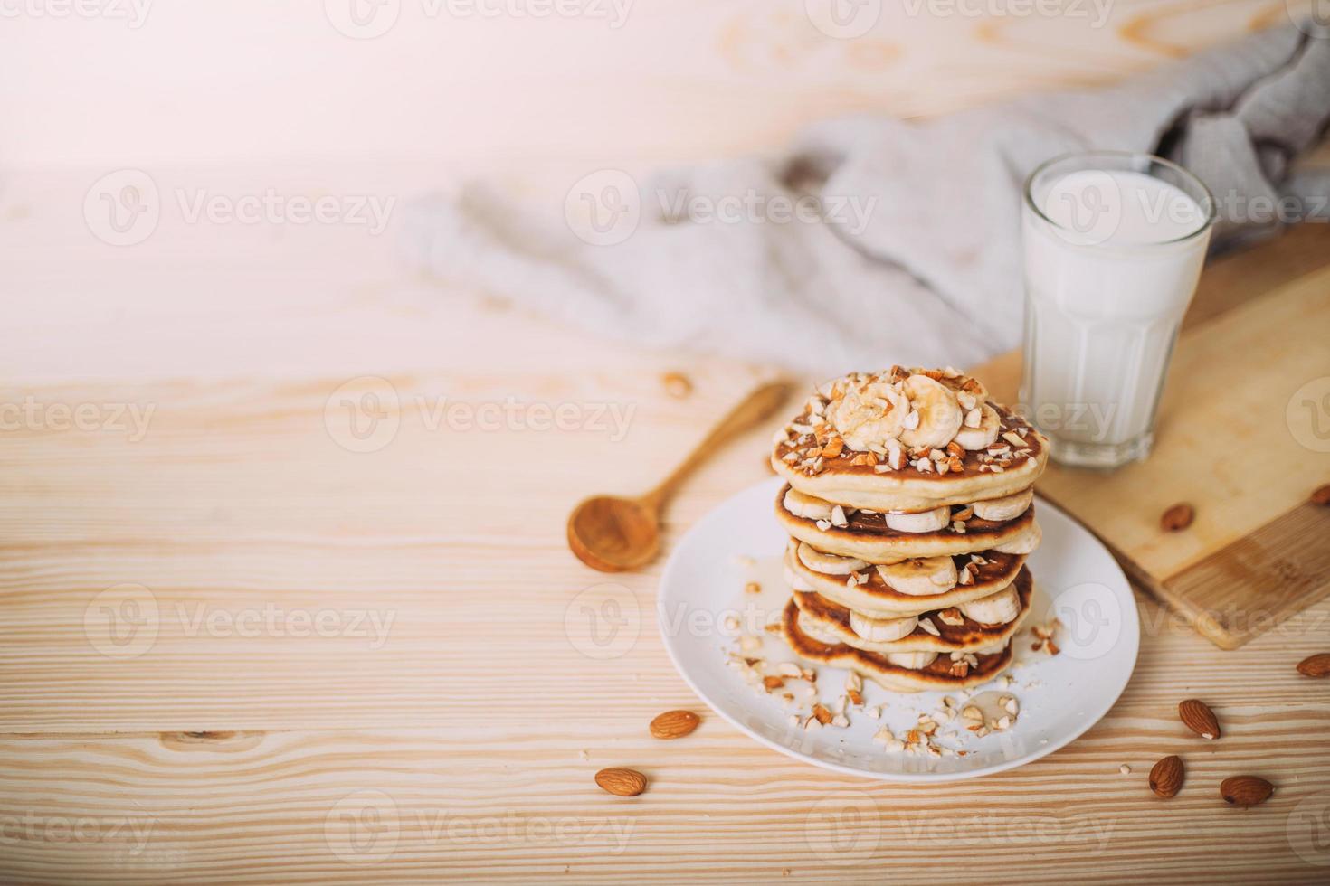 Stack of delicious pancakes with honey, nuts and slices of banana. photo