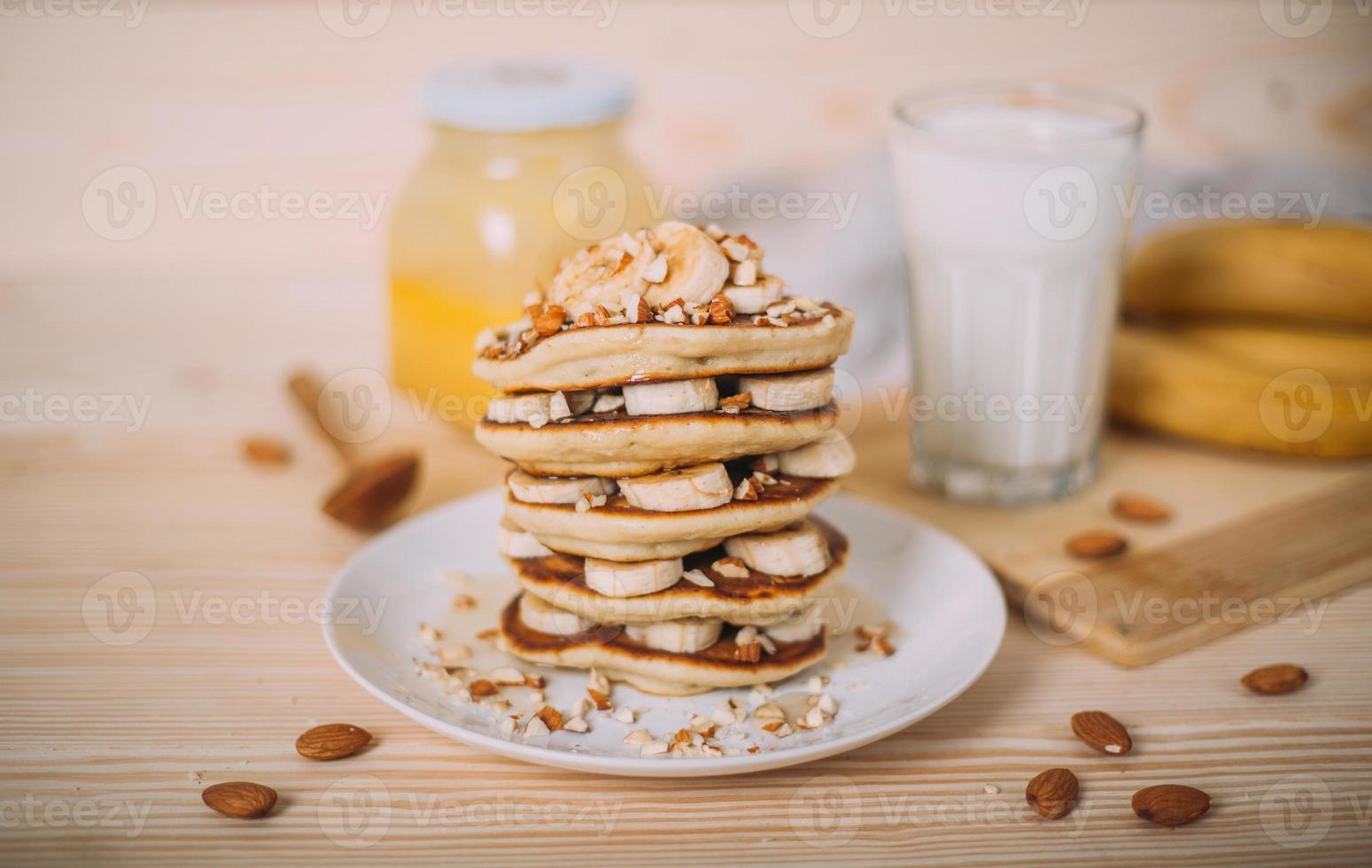 Stack of delicious pancakes with honey, nuts and slices of banana. photo