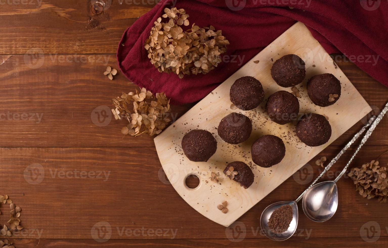 bolas de cacao, pasteles de trufas de chocolate a bordo sobre fondo de madera foto