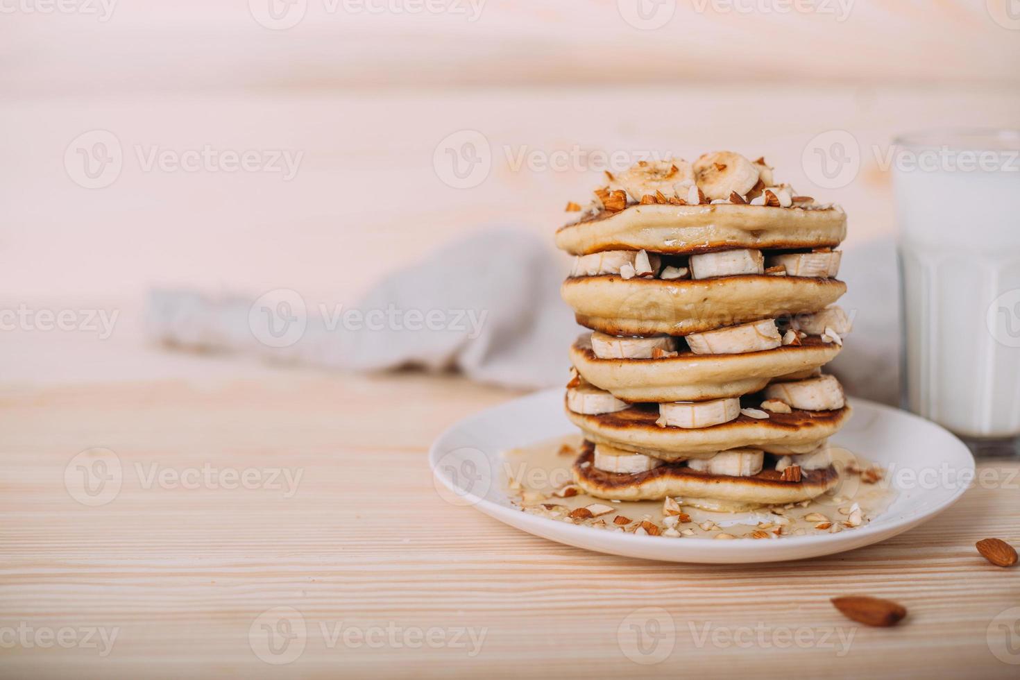 Stack of delicious pancakes with honey, nuts and slices of banana. photo
