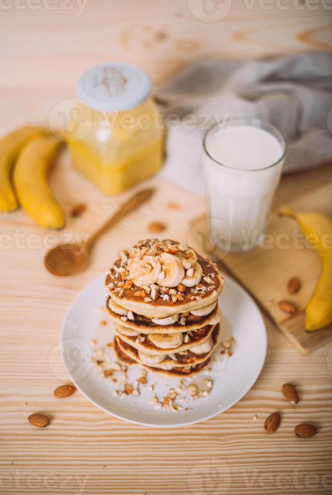 Stack of delicious pancakes with honey, nuts and slices of banana. photo
