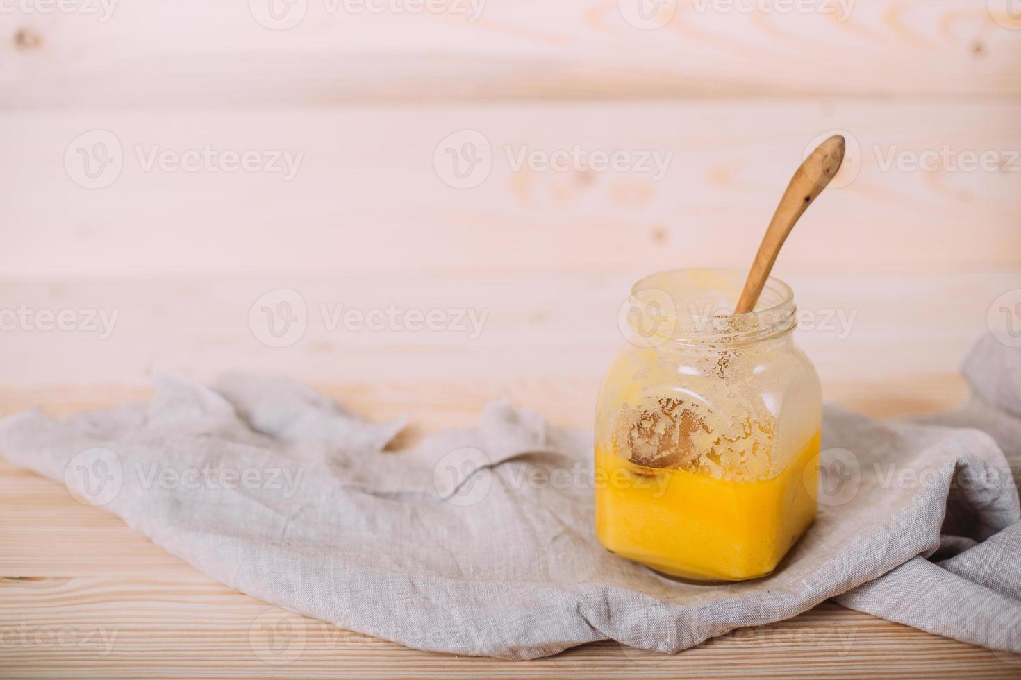 A jar of solid honey and cloth on wooden background. photo