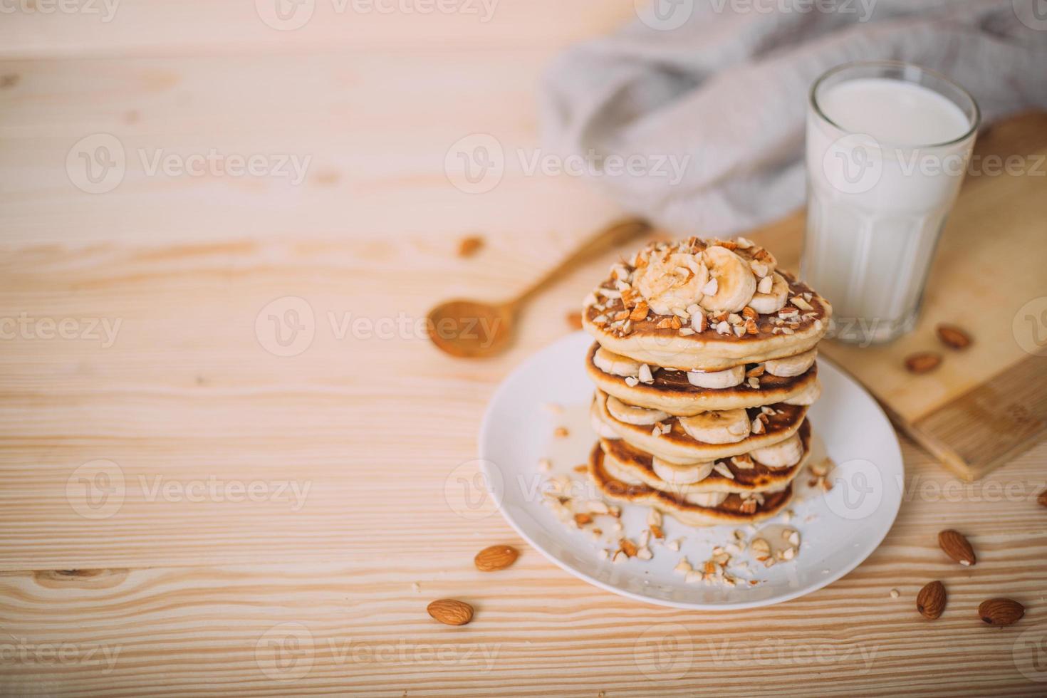 Stack of delicious pancakes with honey, nuts and slices of banana. photo
