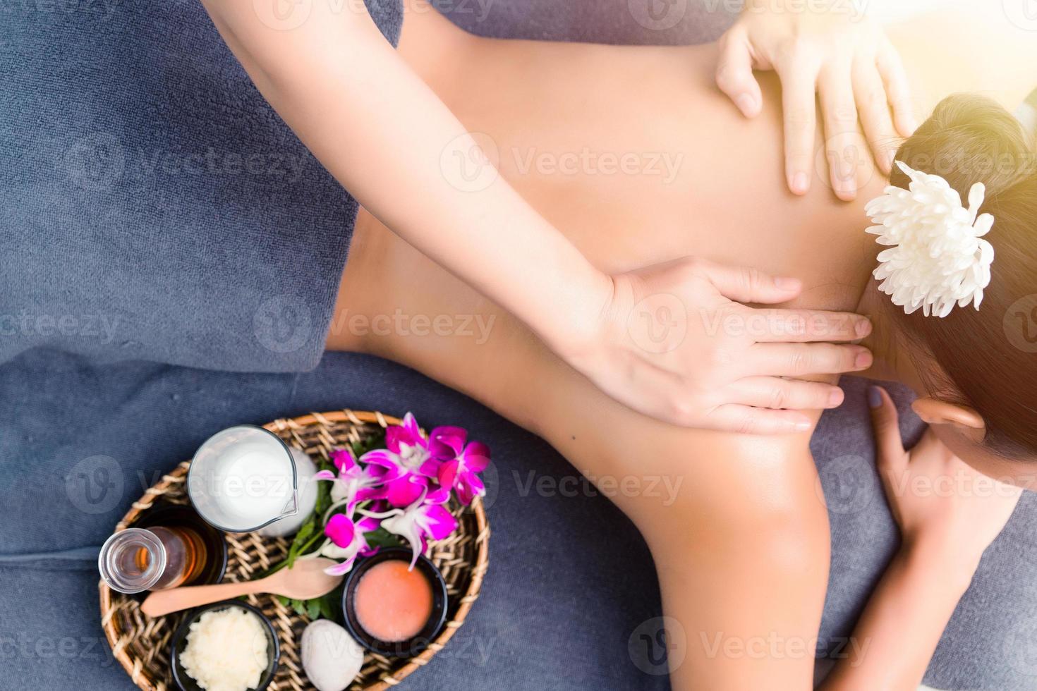 Massage and body care. Young woman tan or honey skin receiving relaxing shoulders massaging in a spa house. Beautiful woman having massage in the spa salon for beauty care. photo